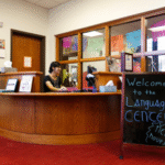 a person sitting at a desk with a sign that says welcome to the language center