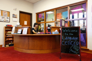 a person sitting at a desk with a sign that says welcome to the language center