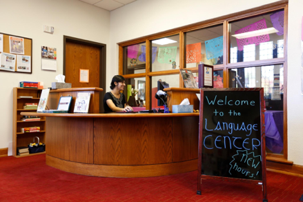 a person sitting at a desk with a sign that says welcome to the language center
